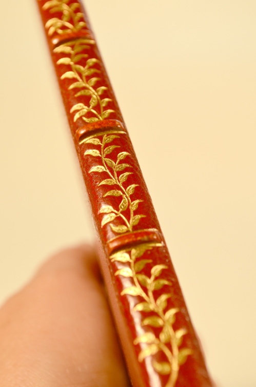 A Detail of the Spoine of "The Passionate Pilgrim", showing the curving tendril or vine which rides the spine in a sinuous curve, interrupted by the spine hubs.  The curves here made of gouge tools, and the leaves tooled separately.
